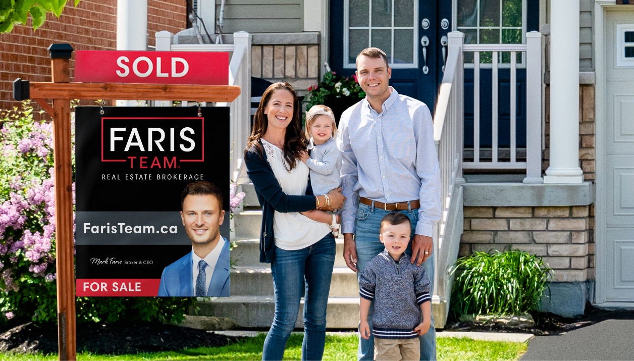 A young family smiling, standing next to a Faris Team Sold sign.